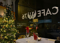 View through the Cafe V76 front window — angel wings logo and warm light